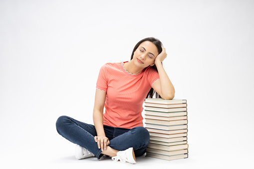 Full length body size photo of young girl book stack relaxation sitting on floor wearing jeans denim pink t-shirt footwear isolated over white background