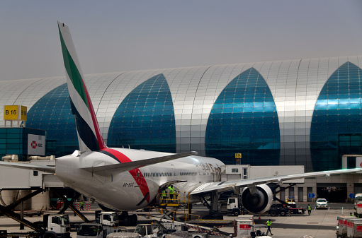 Al Garhoud district, Dubai: Dubai International Airport, terminal 3 with its teardrop windows - Emirates aircraft at a gate position (A6-EGG - Boeing 777-31H ER) . Futuristic glass and steel façade, the terminal was designed by Aéroports de Paris (ADPi) as the hub for Emirates.