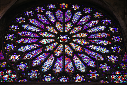 The Basilica of Saint-Denisis a large former medieval abbey church and present cathedral in the commune of Saint-Denis, a northern suburb of Paris. The church was completed in 1144 and widely considered the first structure to employ all of the elements of Gothic architecture. The image shows the ceiling and stained glass windows of that magnificant cathedral.