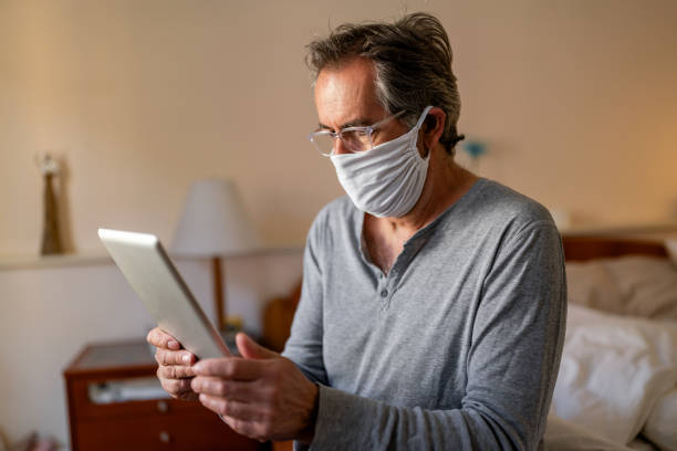 istock Senior man holding digital tablet computer conference calling by social distance virtual family online chat meeting or watching video sitting on couch at home. 2114403332