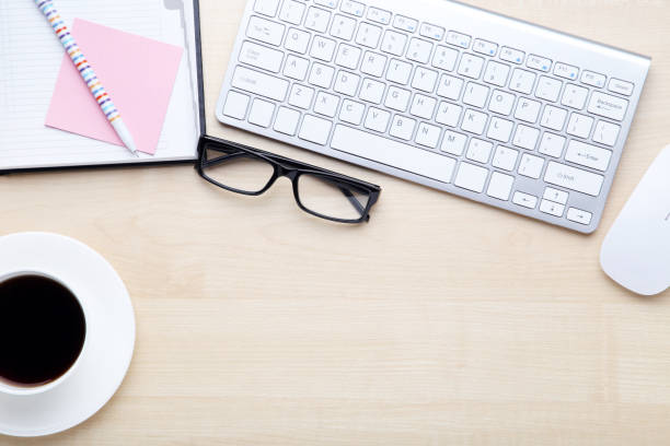 istock Computer keyboard with notepad, glasses and cup of coffee on wooden table 2114414898