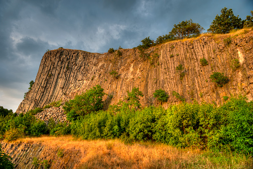 Steep flank of Hegyestű Geológiai Bemutatóhely, a mountain of solidified basalt columns on Lake Balaton, Hungary in the warm evening or morning light of the sun