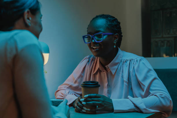 istock Two female colleagues talking in the office cafeteria in the night shift 2114418070