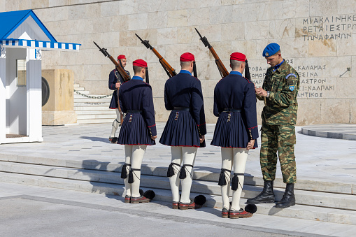 Athens, Greece - October 19, 2022: Changing of the Guard in front of Greek Parliament (Old Royal Palace) by Evzones, Greek representative military formation. On a background Tomb of Unknown Soldier.