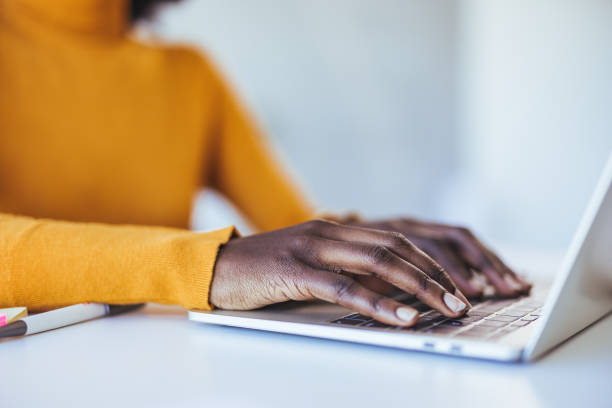 istock Black woman typing and browsing on a laptop in an office alone. 2114430548
