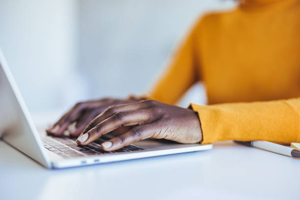 istock Black woman typing and browsing on a laptop in an office alone 2114430561