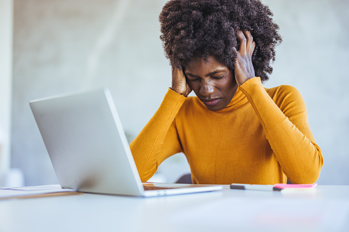 African american female employee stressed while working, paperwork, accounting. Tired businesswoman has a headache at the office. Concept of hard work, stress.