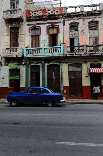 Havana, Cuba-October 8, 2019: Dark blue old American classic car -almendron, yank tank- Buick Special DeLuxe 4-door Sedan 1952 drives down San Lazaro St past a row of early 1900s Eclectic style houses