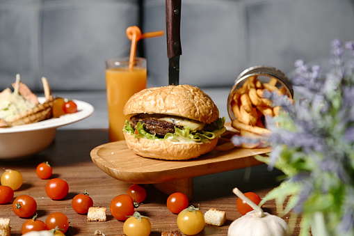 A delicious burger with all the fixings and a side of crispy fries placed on a wooden table.