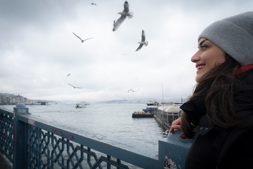 Young woman walking on the Galata Bridge in Istanbul, Turkey.