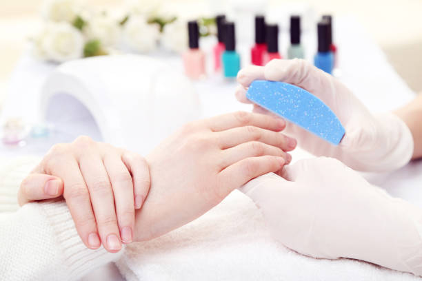 istock Manicurist in gloves making manicure for client by nail file 2114475958