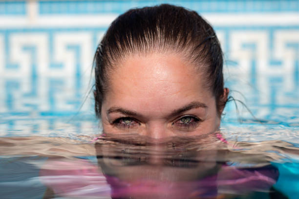 istock Happy woman diving into a pool. 2114489481
