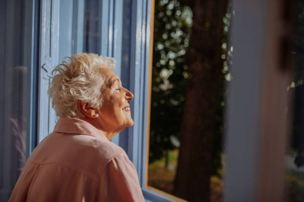istock Elderly woman feeling the breeze trough the window 2114494706