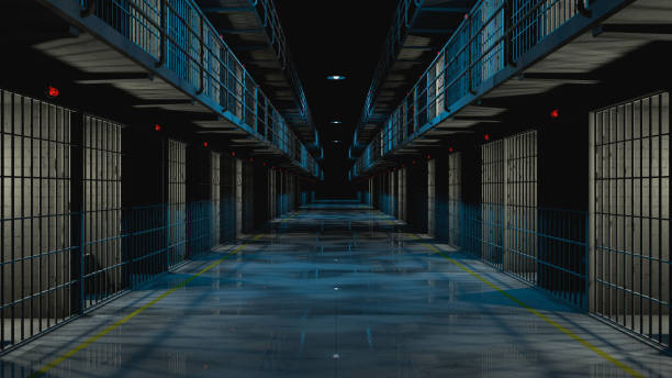 Inside prison corridor at night.  cells with lights on and wet floor.