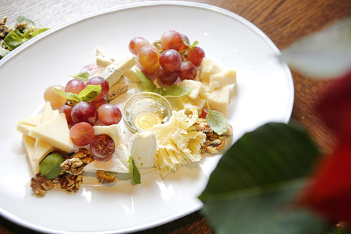 A white plate is adorned with a variety of grapes and cheese, creating a delicious and appetizing arrangement.