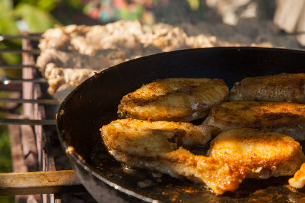 Pan with frying fish steak on the fire. Outdoor kitchen. Summer barbeque and vacation.
