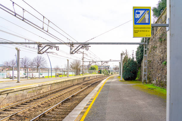 train platform with a yellow line so that passengers do not pass at risk of falling onto the line. Information sign not to cross the yellow line.Image taken in February 2024