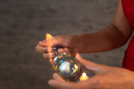 Close-up of the masseur's hands burning a stick inside a glass jar for vacuum therapy, copy space