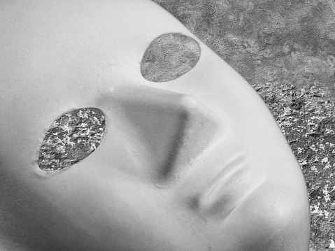 Black and white image of white paper mache mask in close up