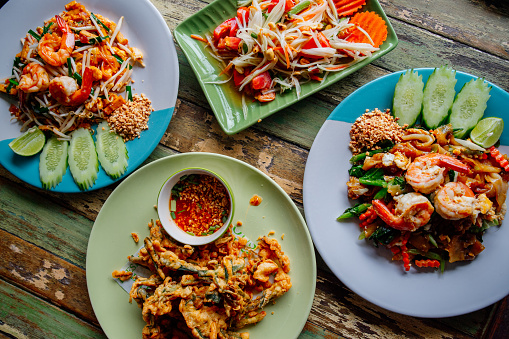 Traditional Thai dishes served at restaurant: pad thai with shrimps, som tam salad and stir fried morning glory. Thai food