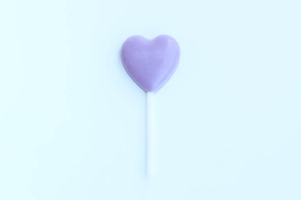 Purple heart shaped lollipop on blue background, Chocolate candy