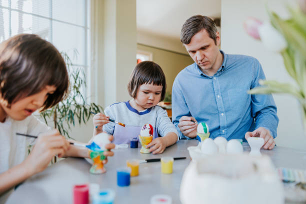 istock Father and daughters gathered around the kitchen table, joyfully painting Easter eggs together 2114627697