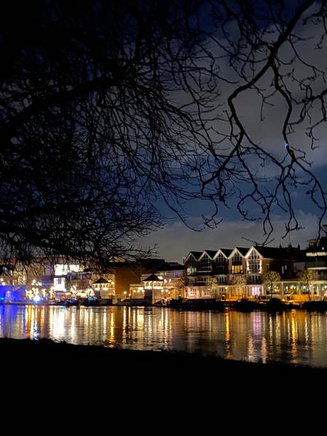 istock Kingston upon Thames Riverside at Night Shops and Restaurant Lights Twinkling and Reflecting in the Water River Thames Tree Branches Light Atmospheric Shopping 2114636611