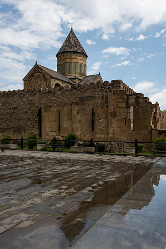 The Svetitskhoveli Cathedral, an Orthodox Christian cathedral located in the center of the historic town of Mtskheta, Georgia, reflected in a puddle following a rain storm.