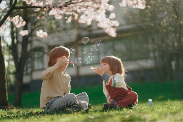 istock brothers blowing bubbles in the park. 2114645063