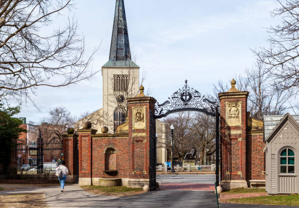 Cambridge, Massachusetts, USA - March 25, 2024: Looking out the Johnston Gate from within Harvard Yard. The Johnston Gate is one of the several entrances to Harvard University's Harvard Yard in Cambridge, Massachusetts. Completed in 1889, it opens onto Peabody Street just north of Harvard Square. It was the gift of Samuel Johnston (Harvard College class of 1855). In the background is the First Parish in Cambridge, a Unitarian Universalist church located in Harvard Square in Cambridge.