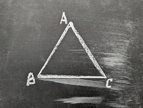 Треугольник нарисованный мелом на черной доске.