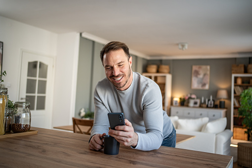 Smiling happy man enjoying a cup of coffee at home