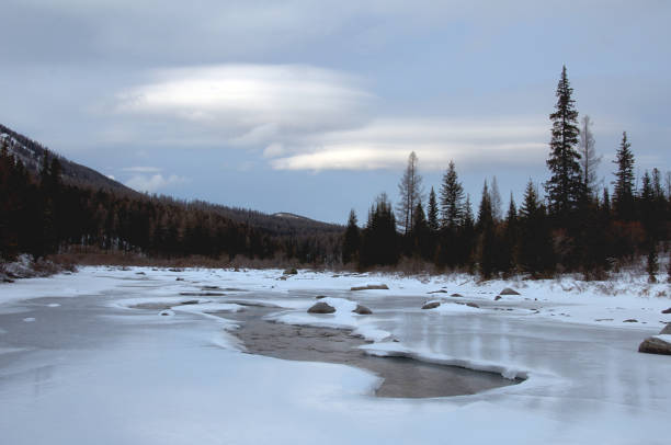 istock Icy river in a winter wonderland under a cloudy sky 2114698699