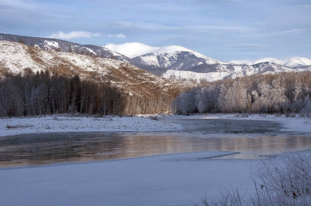istock Snowcovered mountain landscape with a frozen river and cloudy sky. 2114716608