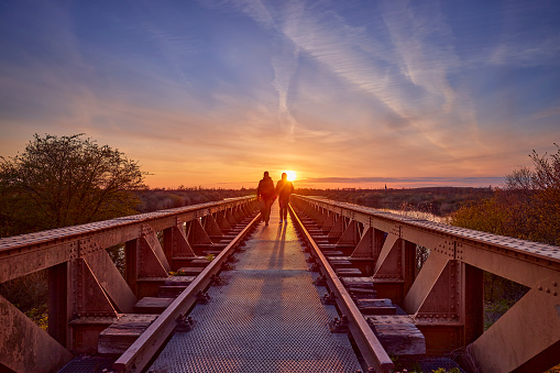 Two people on the  Moerputten old railway bridge in Den Bosch,  The netherlands during sunset.