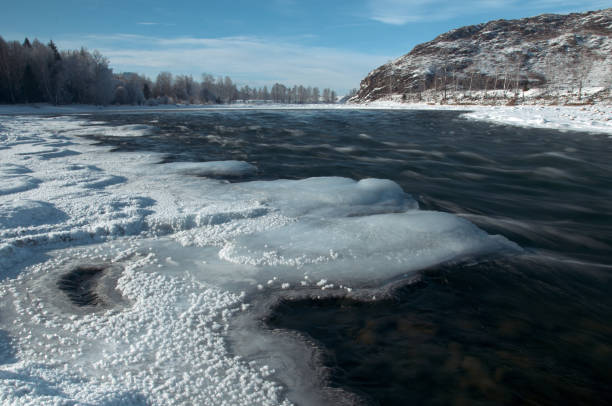 istock A frozen river bank with a distant mountain under a cloudy sky 2114729697