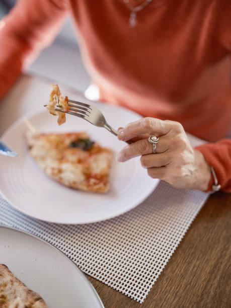 Senior woman eating pizza at RV table