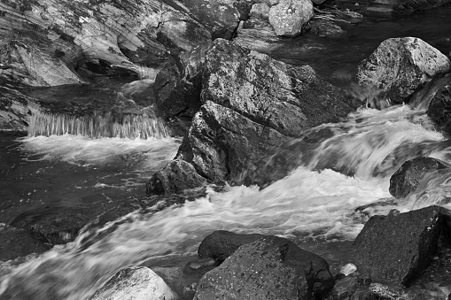 Rocky riverbed between falls at Kent Falls State Park, Connecticut. Early spring after rain. Black-and-white photo.