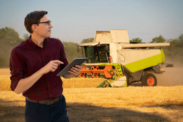 istock Farmer with digital tablet on a background of harvester. 2114745399