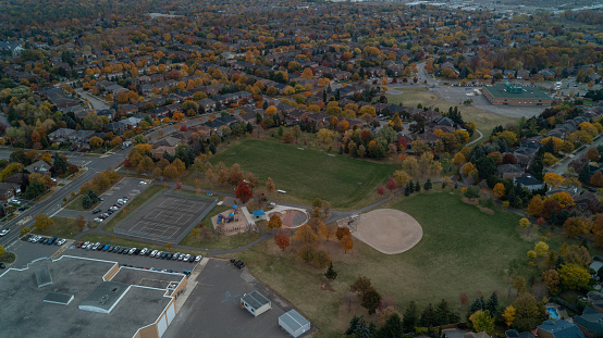 An aerial view of a Park with a Baseball Dimond and houses in the suburbs during Fall
