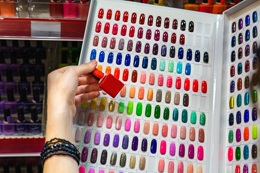 Woman chooses nail polish in a cosmetics store
