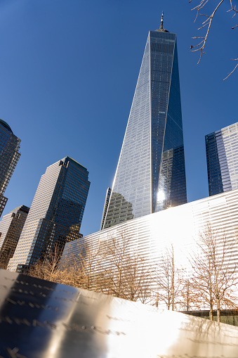 Manhattan, New York, USA - March, 2024.  World Trade Centre memorial ground zero waterfall feature with the new World Trade Center Freedom building in the background.
The National September 11 Memorial & Museum (also known as the 9/11 Memorial & Museum) is part of the World Trade Center complex, in New York City, created for remembering the September 11 attacks of 2001. The memorial is located at the World Trade Center site, the former location of the Twin Towers that were destroyed during the September 11 attacks. The designer of the Memorial is Israeli-American architect Michael Arad of Handel Architects. Arad worked with landscape-architecture firm Peter Walker and Partners on the design to create two square reflecting pools in the center marking where the Twin Towers stood. A dedication ceremony commemorating the tenth anniversary of the attacks was held at the memorial on September 11, 2011, and it opened to the public the following day. The museum was dedicated on May 15, 2014 Six days later, the museum opened to the public.