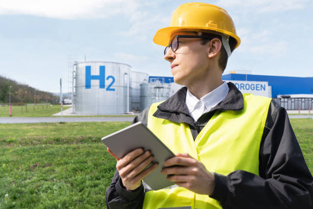 istock Engineer with tablet computer on a background of Hydrogen factory 2114802672