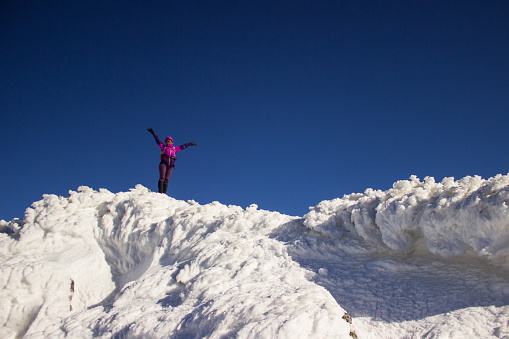 One woman, young female hiker standing on a snow scaped mountain top during the day
