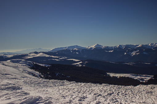 Panoramic view of snowcapped mountain range with clear sky and sunshine