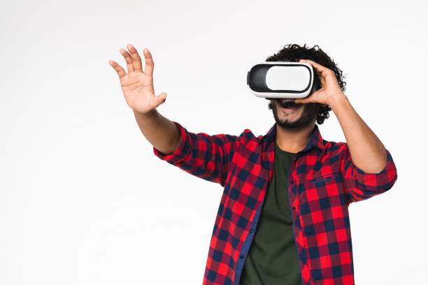 istock Active young Indian man using VR glasses for playing isolated over white background. 2114832974