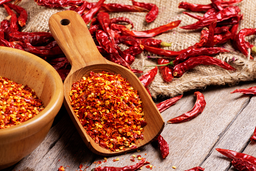Chili powder in a wooden spoon, dried chili peppers and red paprika, spicy, healthy food, top view