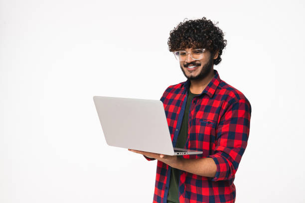 Smiling young Indian man using laptop for remote job isolated over white background.