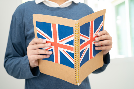 Learn English language, Asian teenage student hold book with flag in course at school.