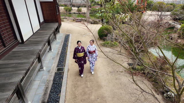 Female friends in kimono walking in shrine